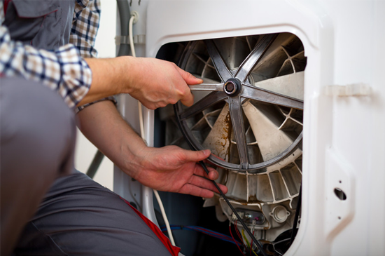 Repairing Washing Machine. Repairman is repairing a washing machine on the white background.