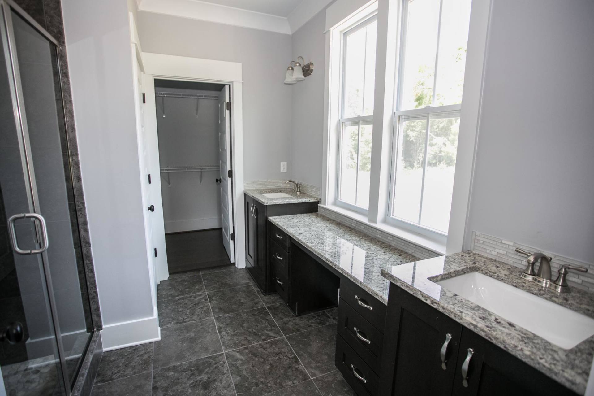A bathroom with two sinks and a walk in shower.