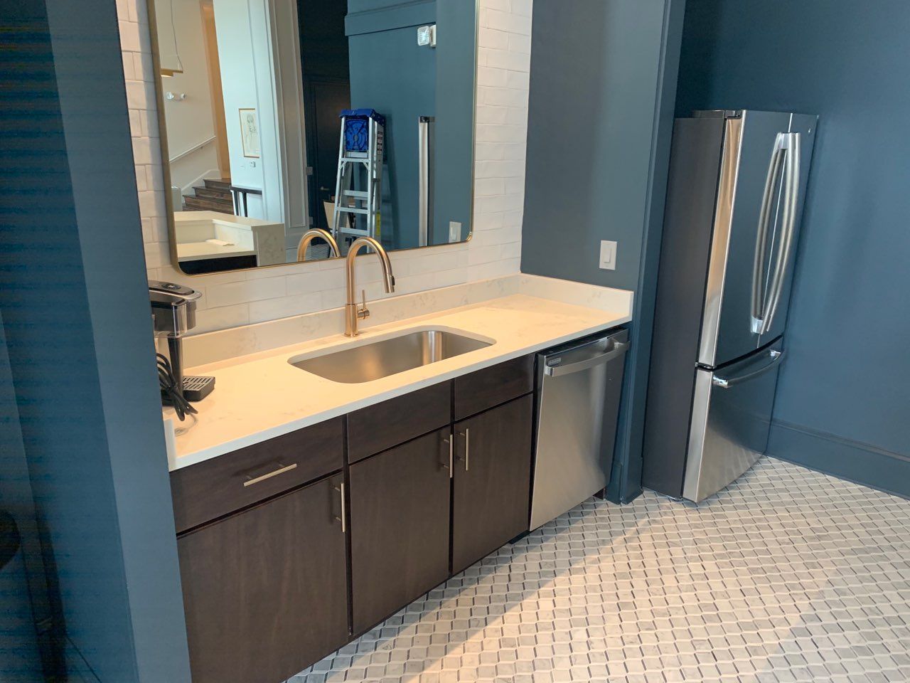 A kitchen with a sink , refrigerator , dishwasher , and mirror.