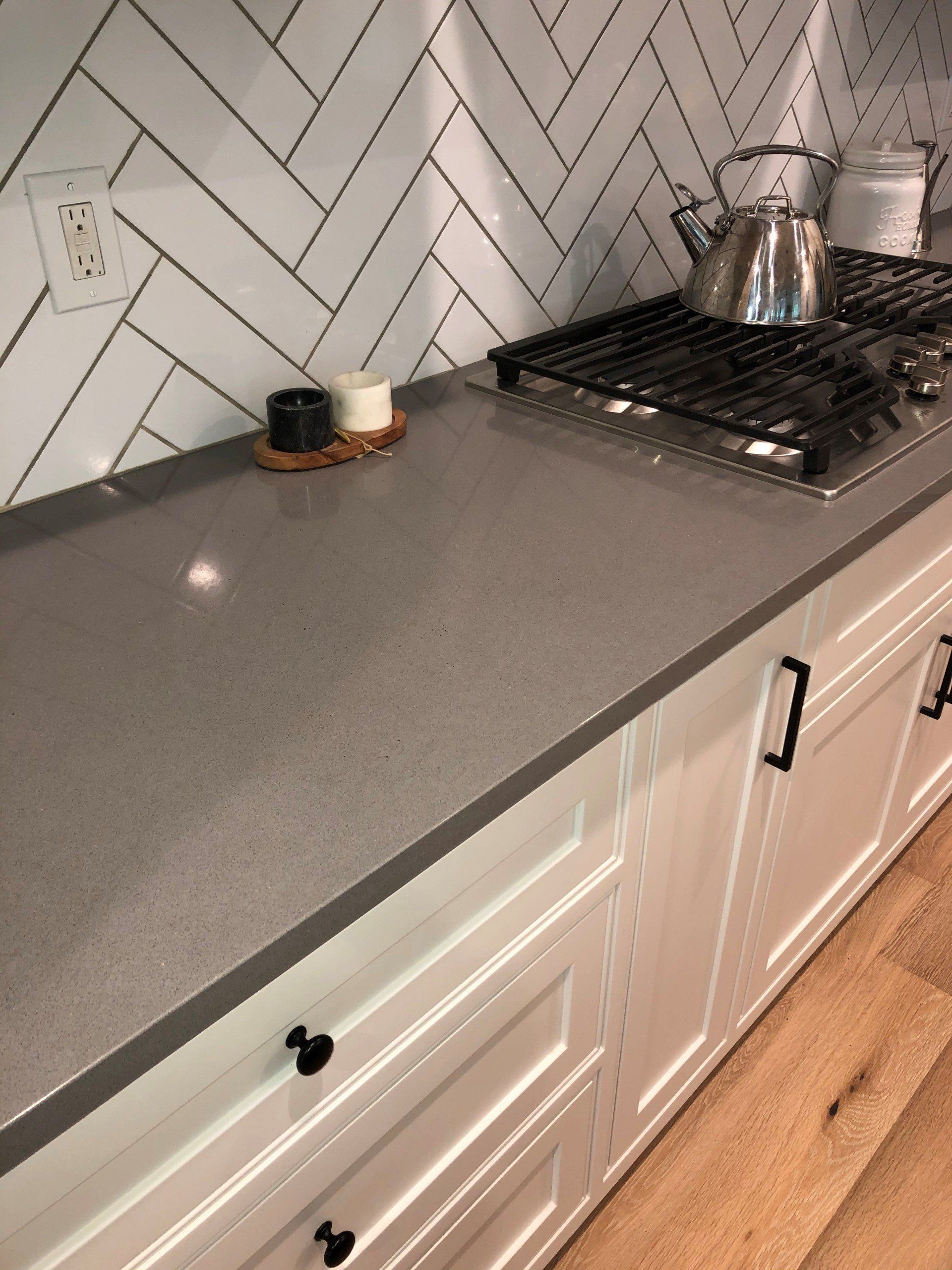 A kitchen with white cabinets and a stove top oven