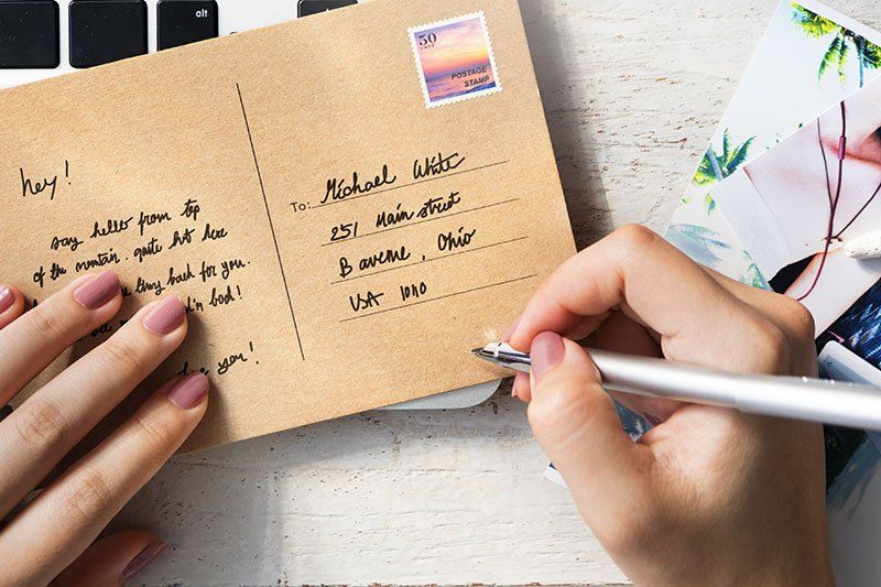 Hands addressing a postcard