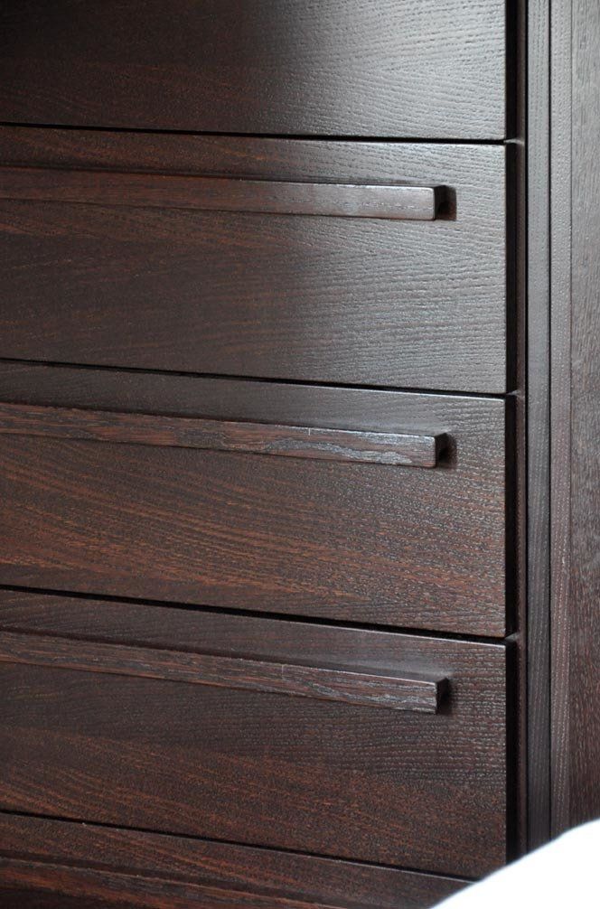 Cassettiera in legno scuro con maniglie orizzontali incassate.
