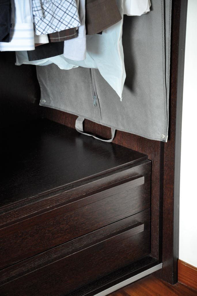 Armadio con cassetto in legno scuro e appendiabiti. Divisorio in tessuto grigio.