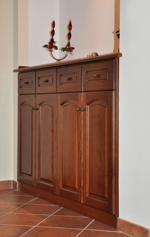 Mobiletto in legno ad angolo con ante e cassetti, sormontato da un candelabro. Marrone, bianco.