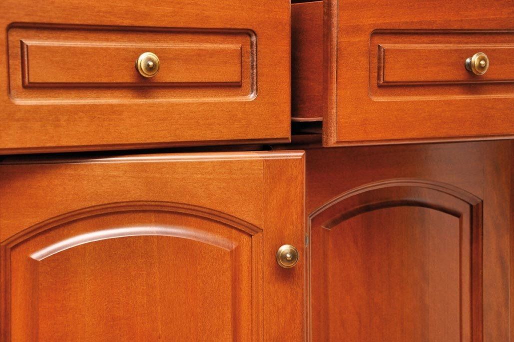 Primo piano dei mobili da cucina in legno; un cassetto e una porta sono leggermente socchiusi.