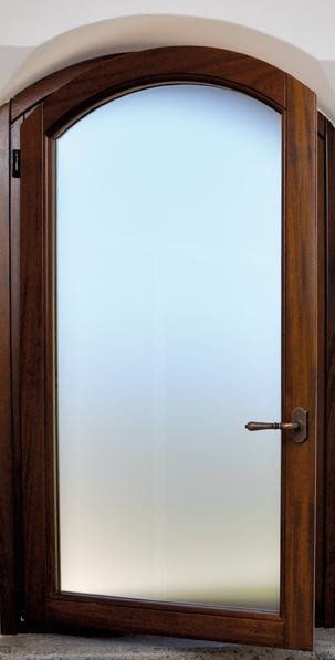 Porta in legno con pannello in vetro smerigliato e parte superiore arcuata, leggermente aperta.