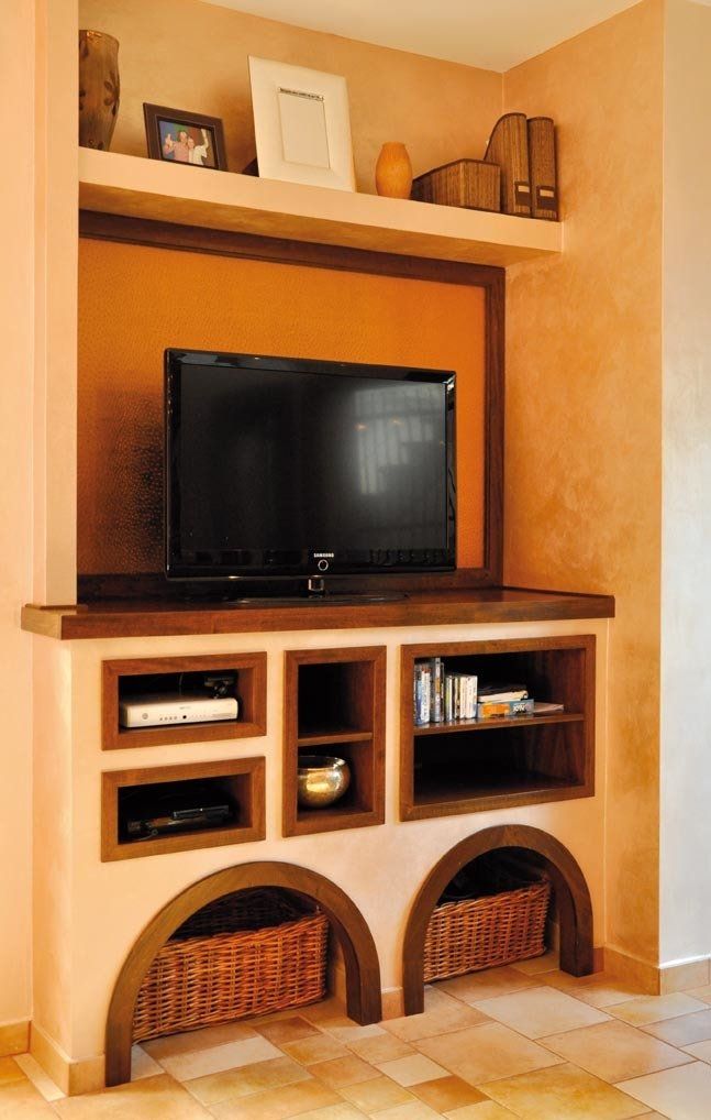Centro di intrattenimento integrato con TV, scaffali, spazio di archiviazione e cestini di vimini ad arco; verniciato nei toni del pesca e del legno scuro.