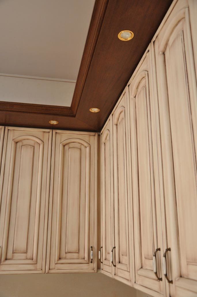 Mobili bianchi anticati con finiture in legno scuro e illuminazione da incasso.