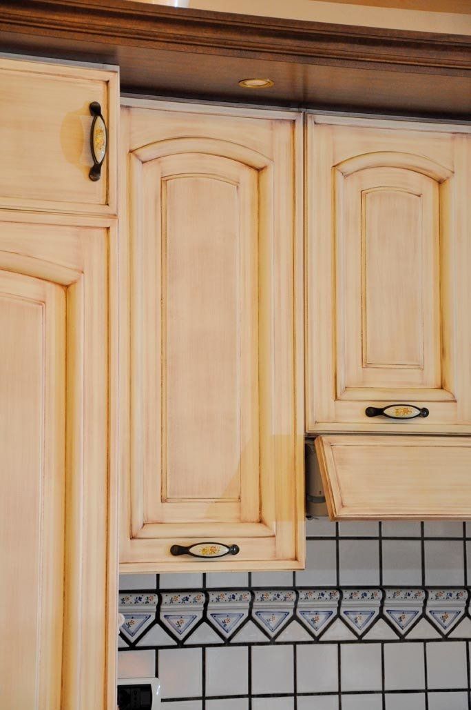 Mobili da cucina beige con ferramenta nera sopra un paraschizzi piastrellato.