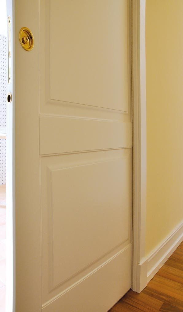 Porta con pannelli bianchi leggermente socchiusa, che rivela interni e finiture di colore chiaro.