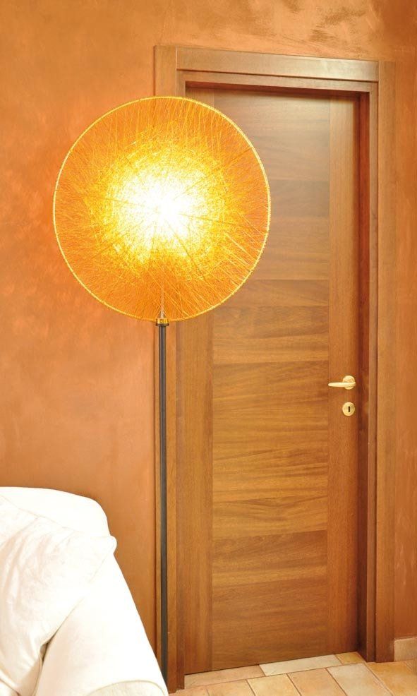 Grande lampada rotonda arancione accanto a una porta marrone in una stanza con pareti arancioni.