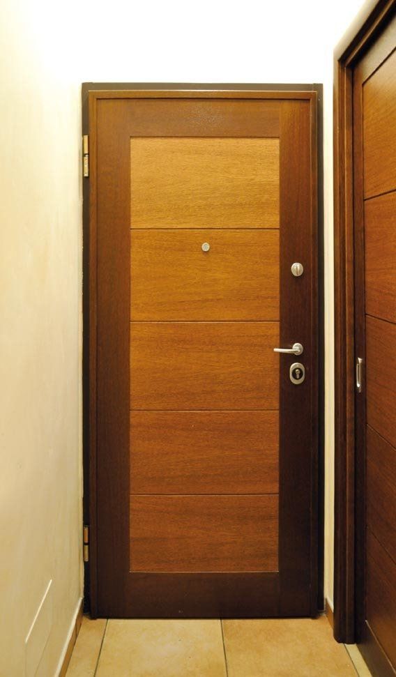 Porta di legno marrone con cornice scura in un corridoio.