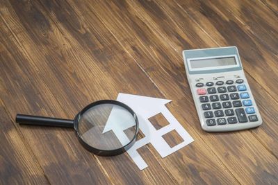 Magnify glass and calculator over a paper house