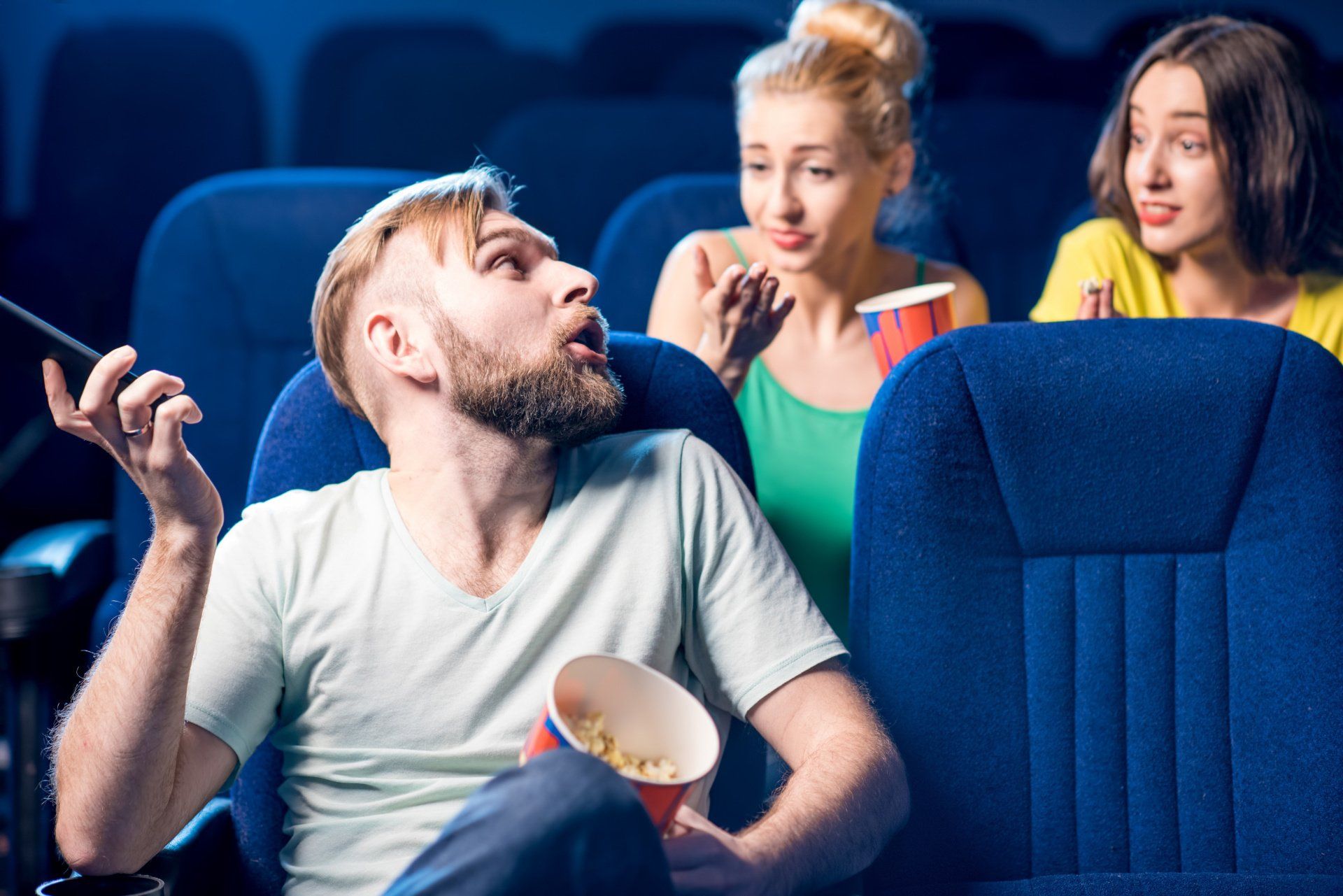 couple of woman, in a cinema, asking a man who is in the row infront of them to not use his mobile