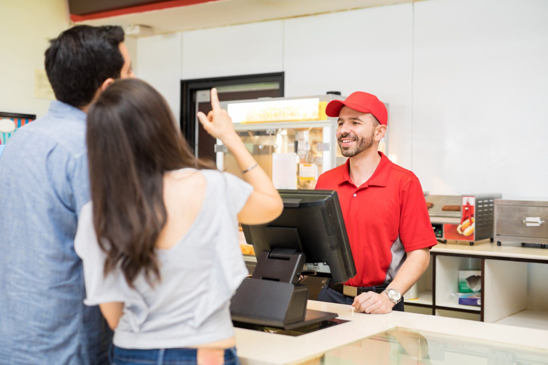 A photograph of a man and woman, at the food counter in a cinema, ordering items