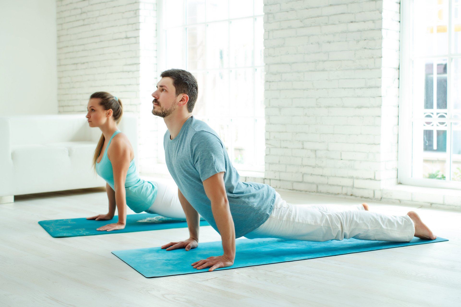 A photograph of a couple on the floor performing a yoga pose