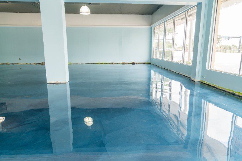 Empty indoor pool with glossy blue water and large windows reflecting light