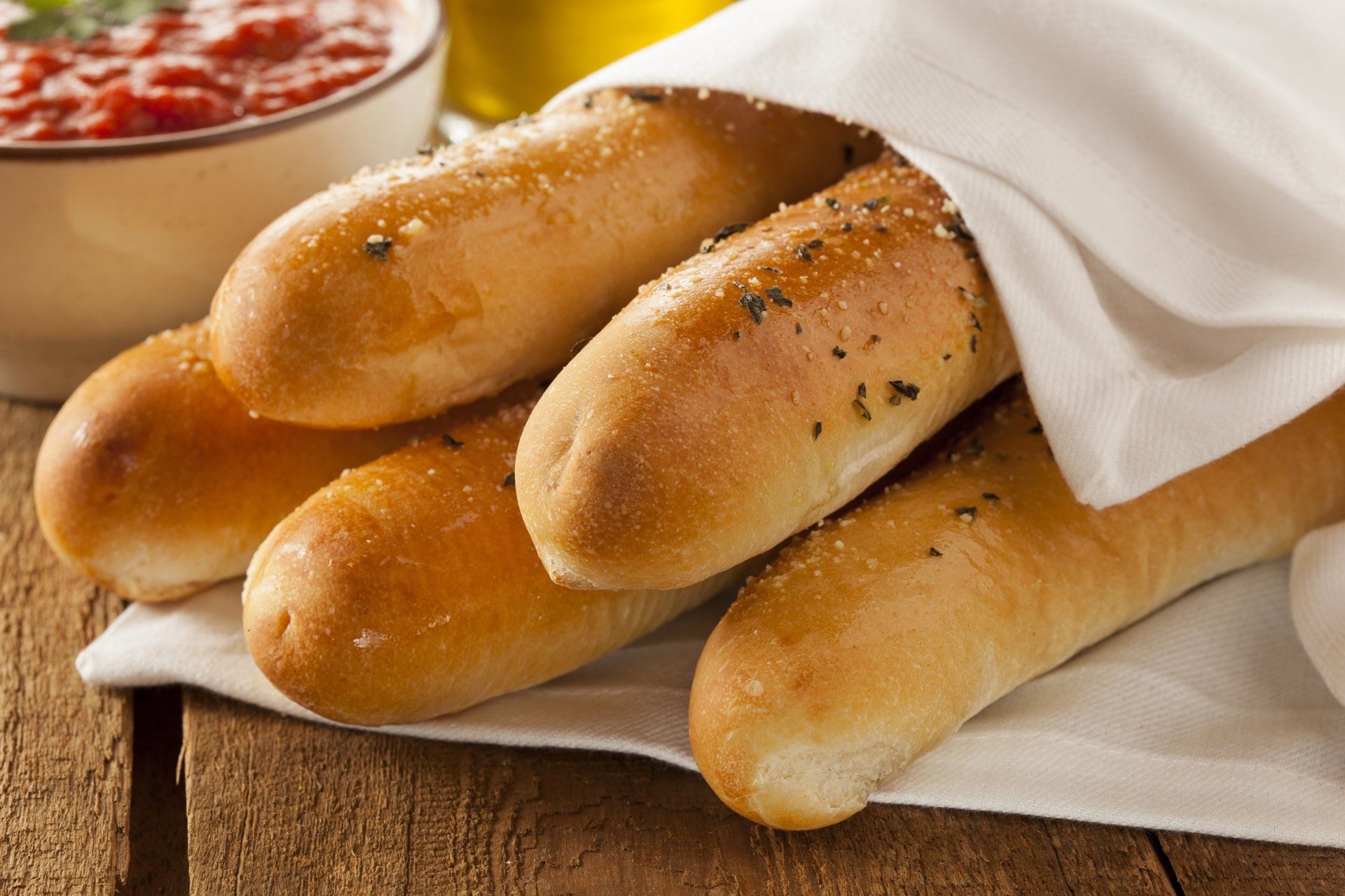 A bunch of garlic bread sticks wrapped in a napkin on a table.