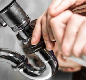 Plumber Repairing a Pipe — Plumbing Services in East Providence, RI Plumber Repairing a Pipe — Plumbing Services in East Providence, RI