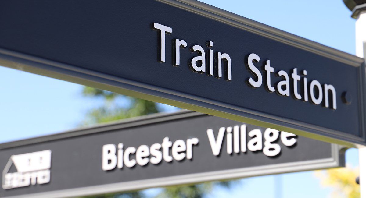 Cast metal directional signs on wayfinding post, part of signage design for Bicester Village