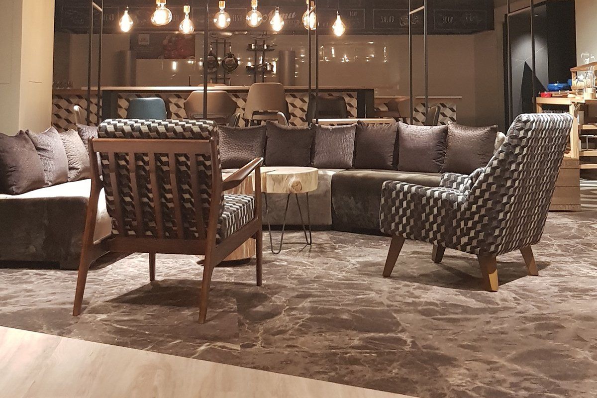 Satelliet showroom with a sectional sofa and two armchairs. Decorative lighting and marble flooring.