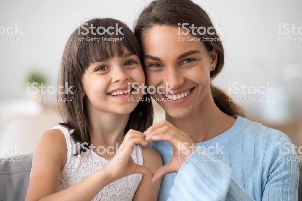 A mother and daughter are making a heart shape with their hands.