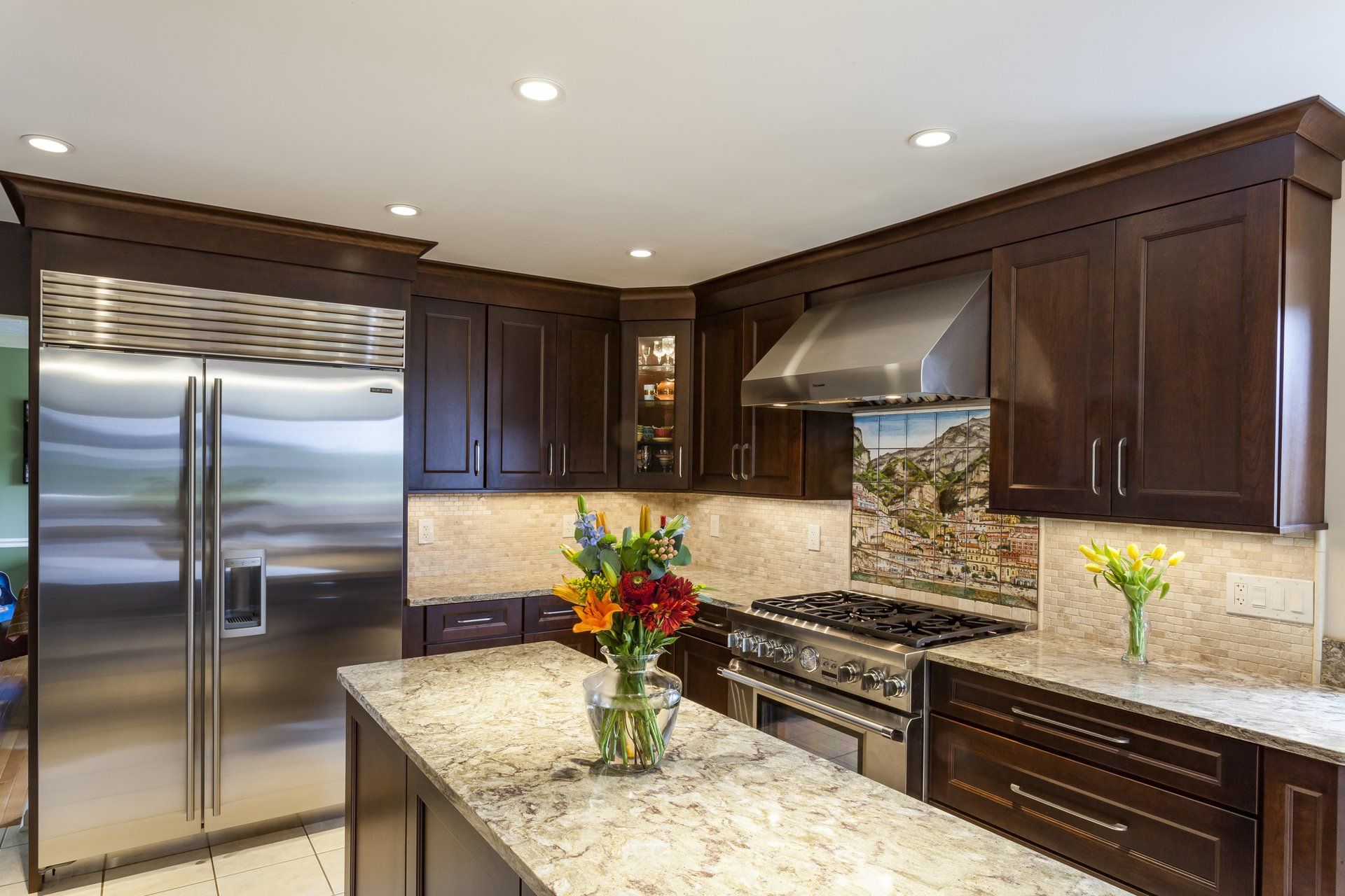 Modern kitchen with stainless steel appliances, dark wood cabinets, granite countertops, and a flower arrangement.