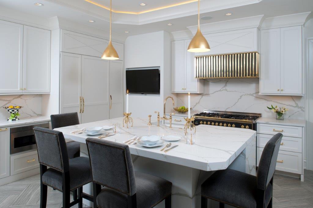Bright modern kitchen with white cabinets, gold pendants, and a marble island with black chairs