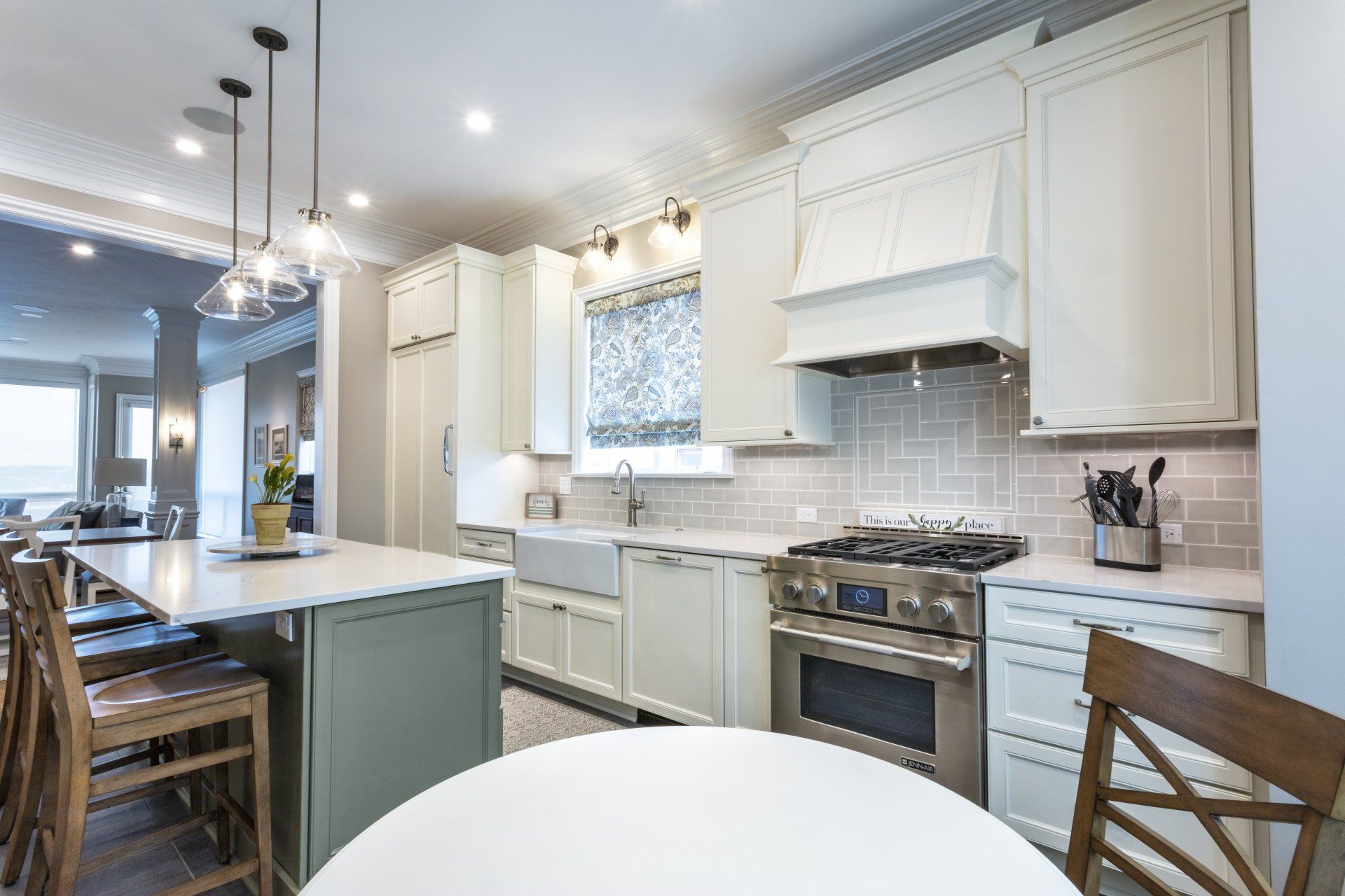 Bright white kitchen with island, pendant lights, and stainless steel stove and hood