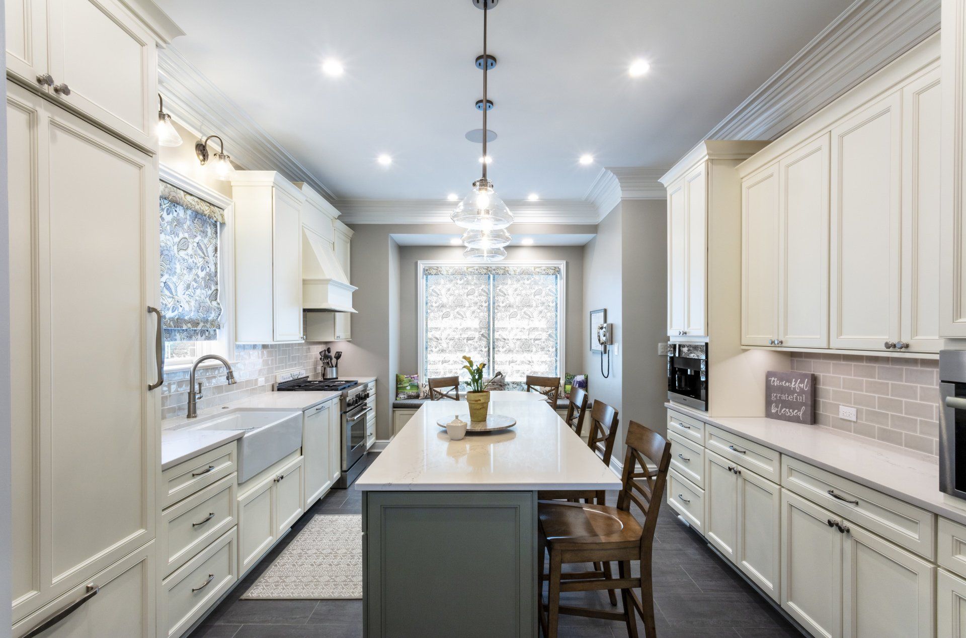 Bright white kitchen with a long island, pendant lights, and large windows.