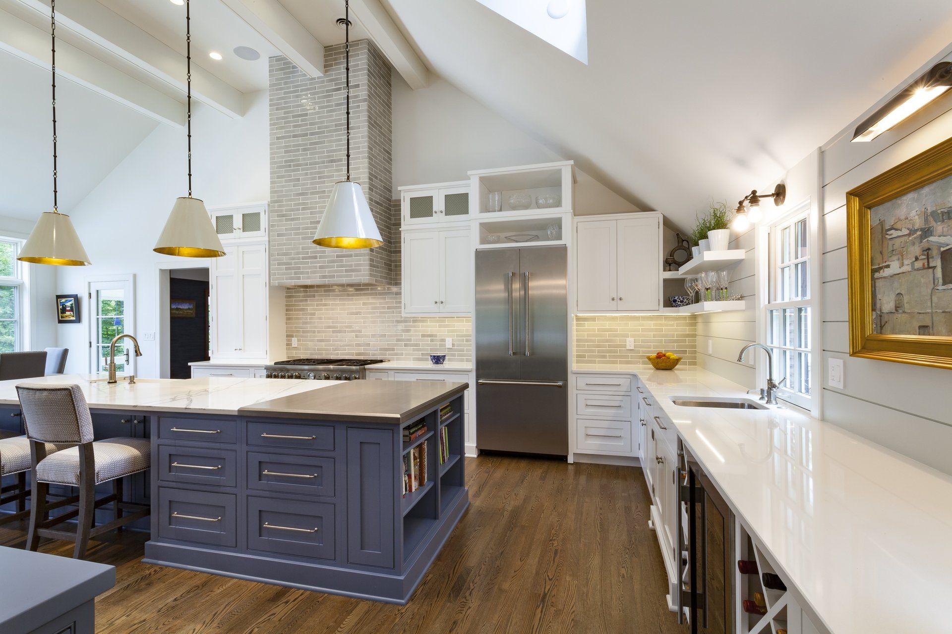 Bright modern kitchen with blue island, white countertops, stainless steel fridge, and pendant lights