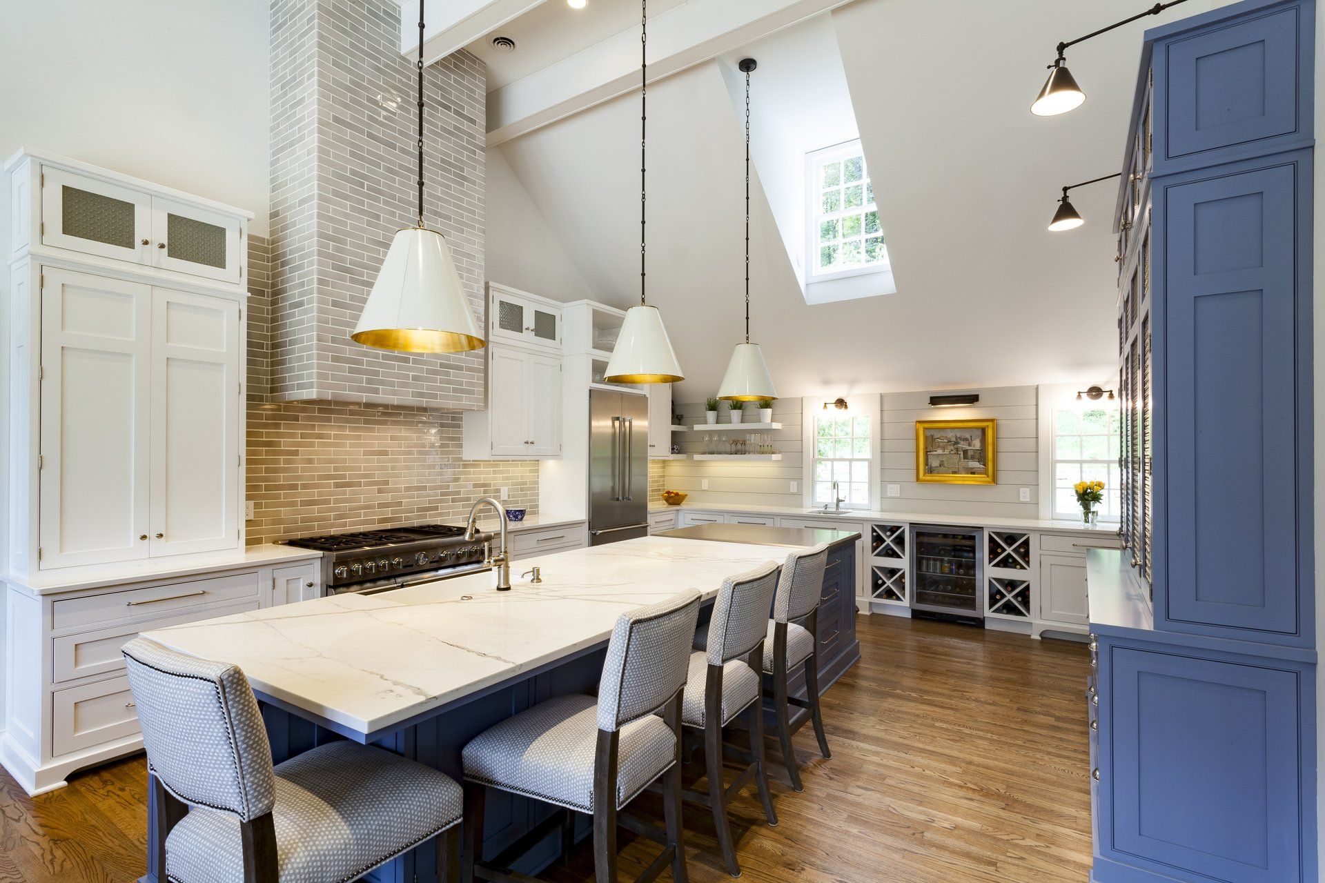 Bright modern kitchen with white cabinetry, long island, pendant lights, and wood floors