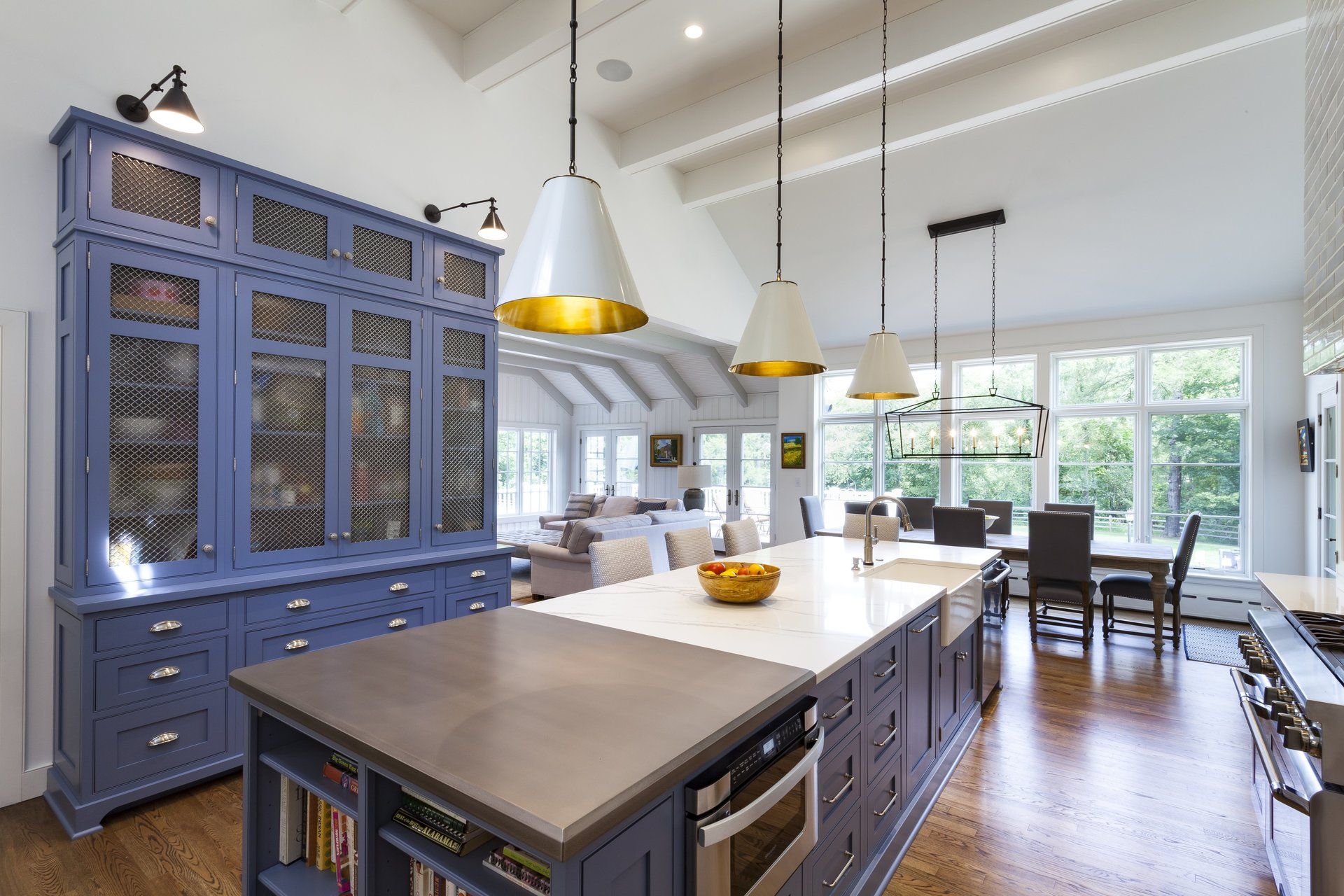Bright kitchen with blue cabinets, large island, pendant lights, and dining area by windows