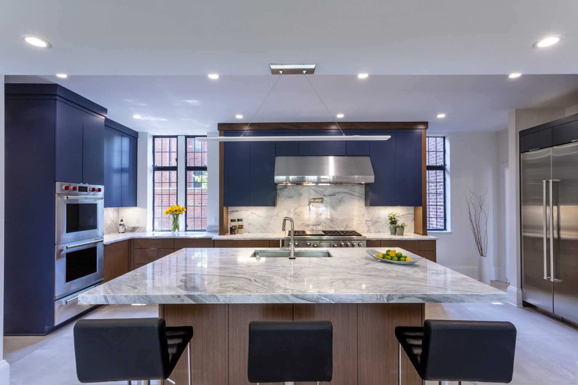 Modern gray kitchen with large island, stainless appliances, and recessed ceiling lights