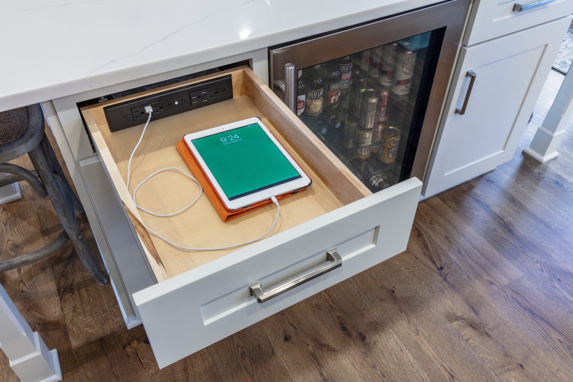 Open kitchen drawer with a hidden compartment holding a green notebook and electronics.