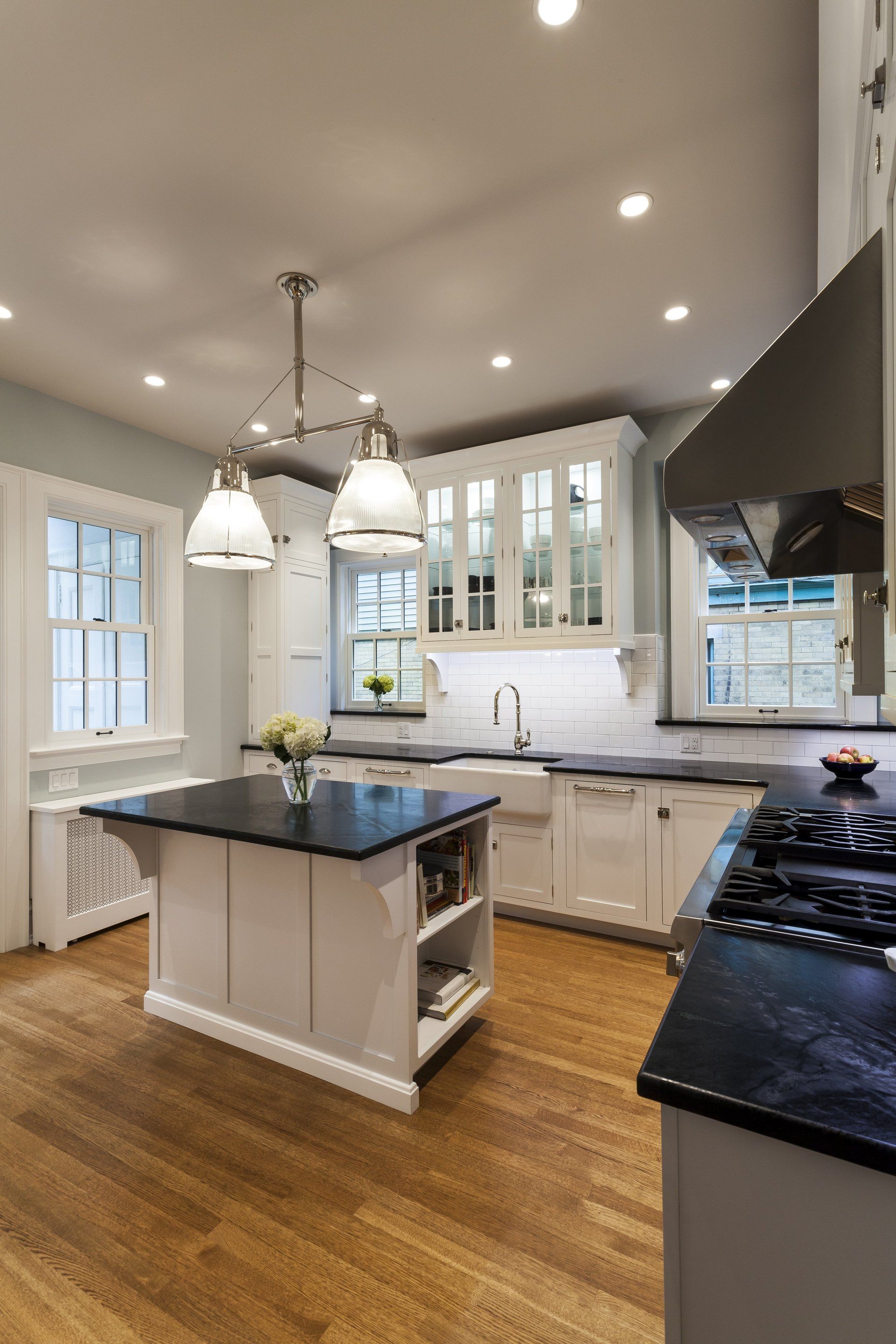Modern kitchen with white cabinets, dark island, black counters, and hardwood floors