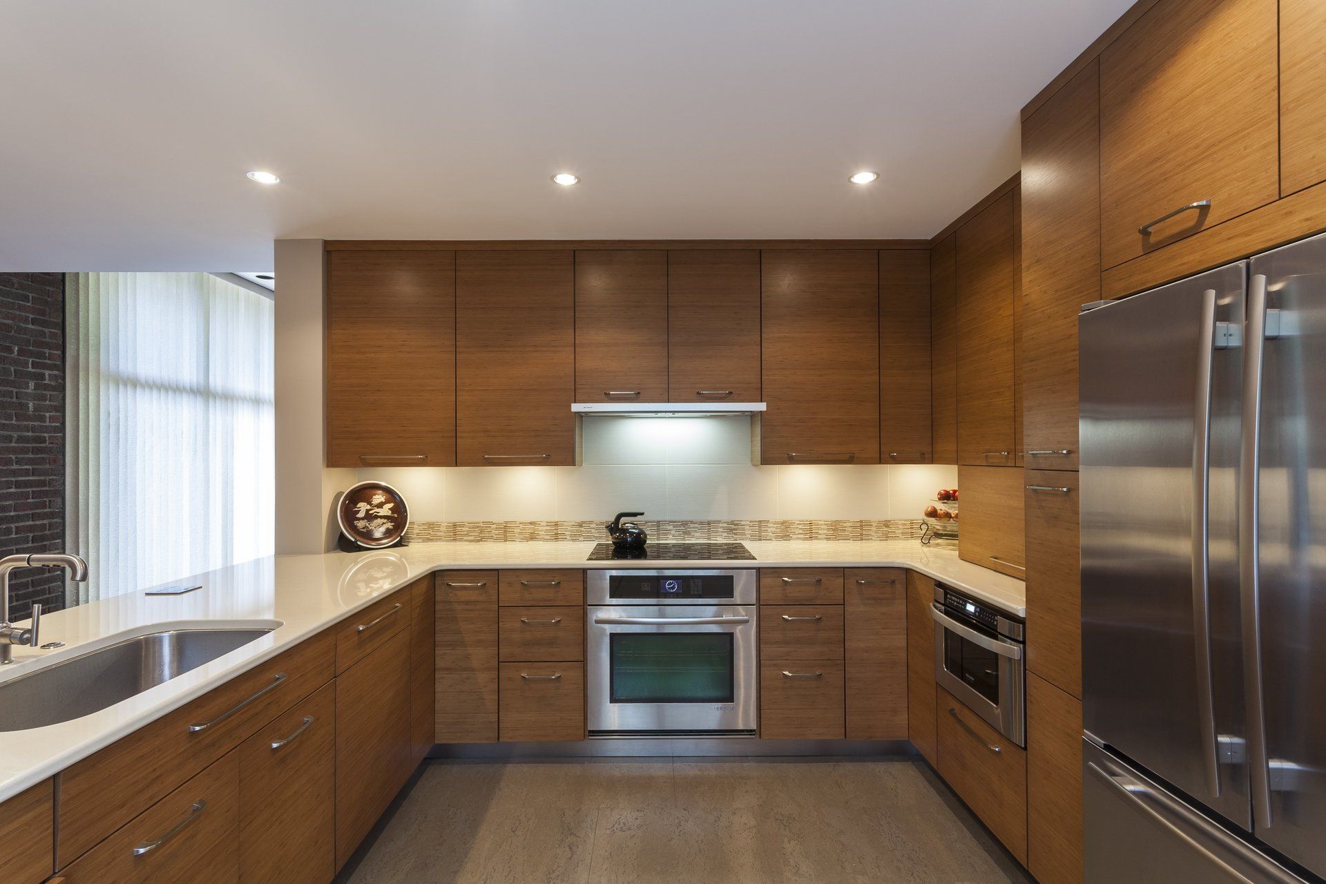 Modern kitchen with wood cabinets, stainless steel appliances, and a large island by a window.