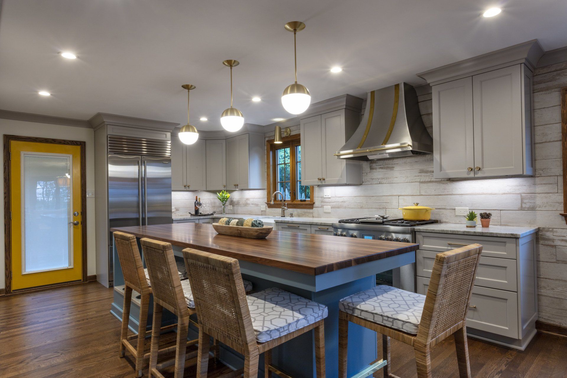 Modern kitchen with island, gray cabinets, stainless appliances, and woven bar stools