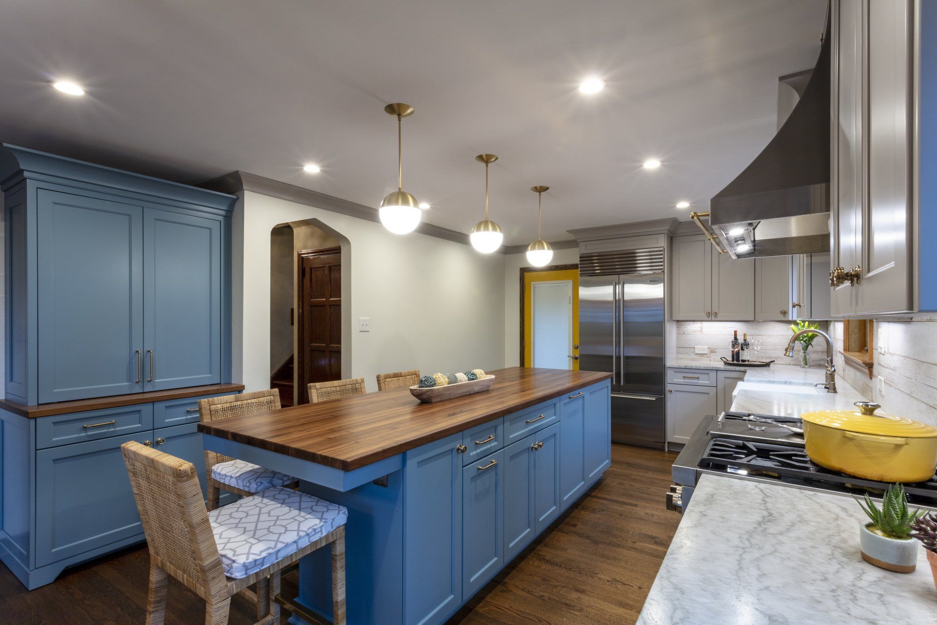 Modern kitchen with blue cabinets, large island, pendant lights, and marble countertops