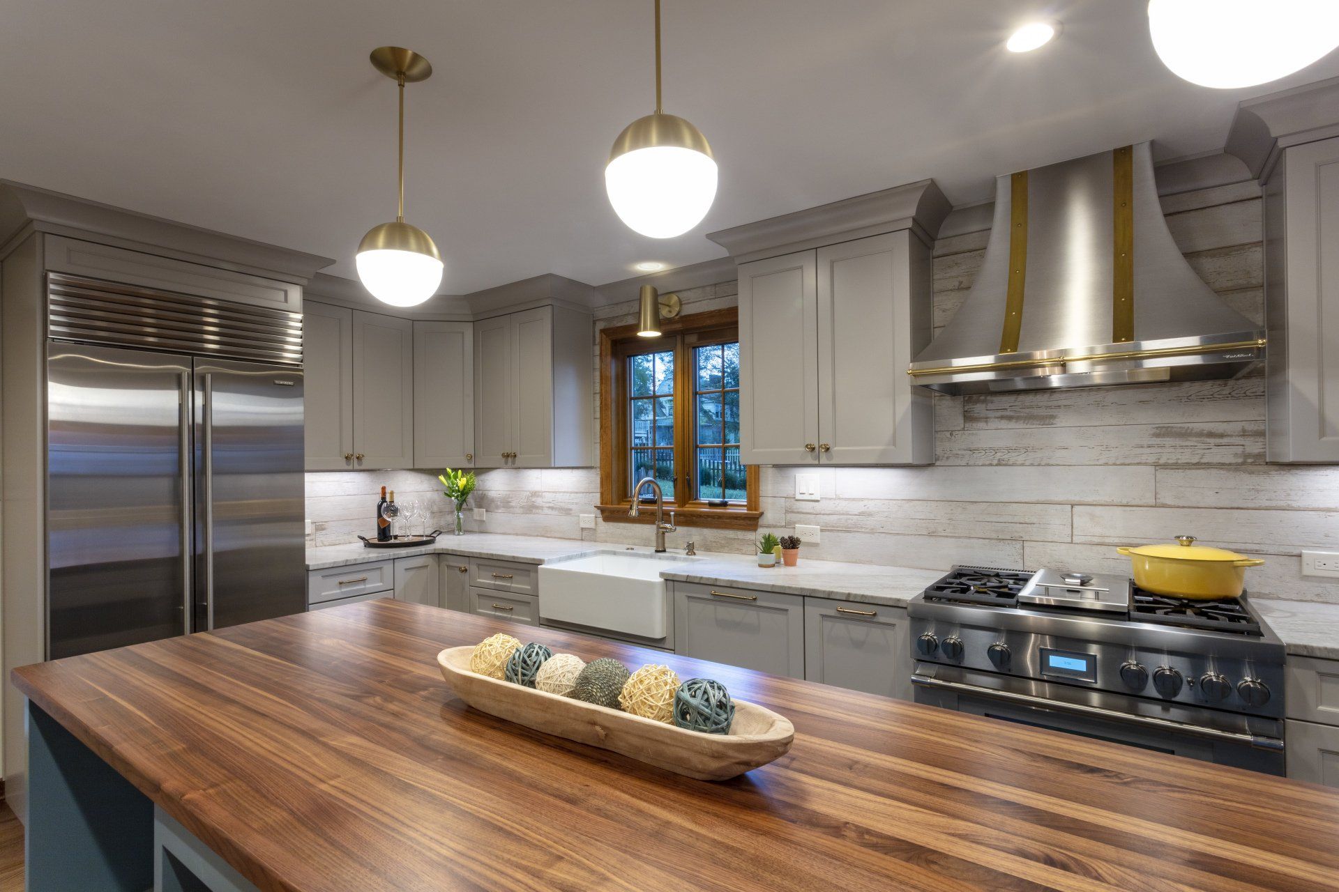 Modern kitchen with stainless steel appliances, gray cabinets, and a wood island countertop
