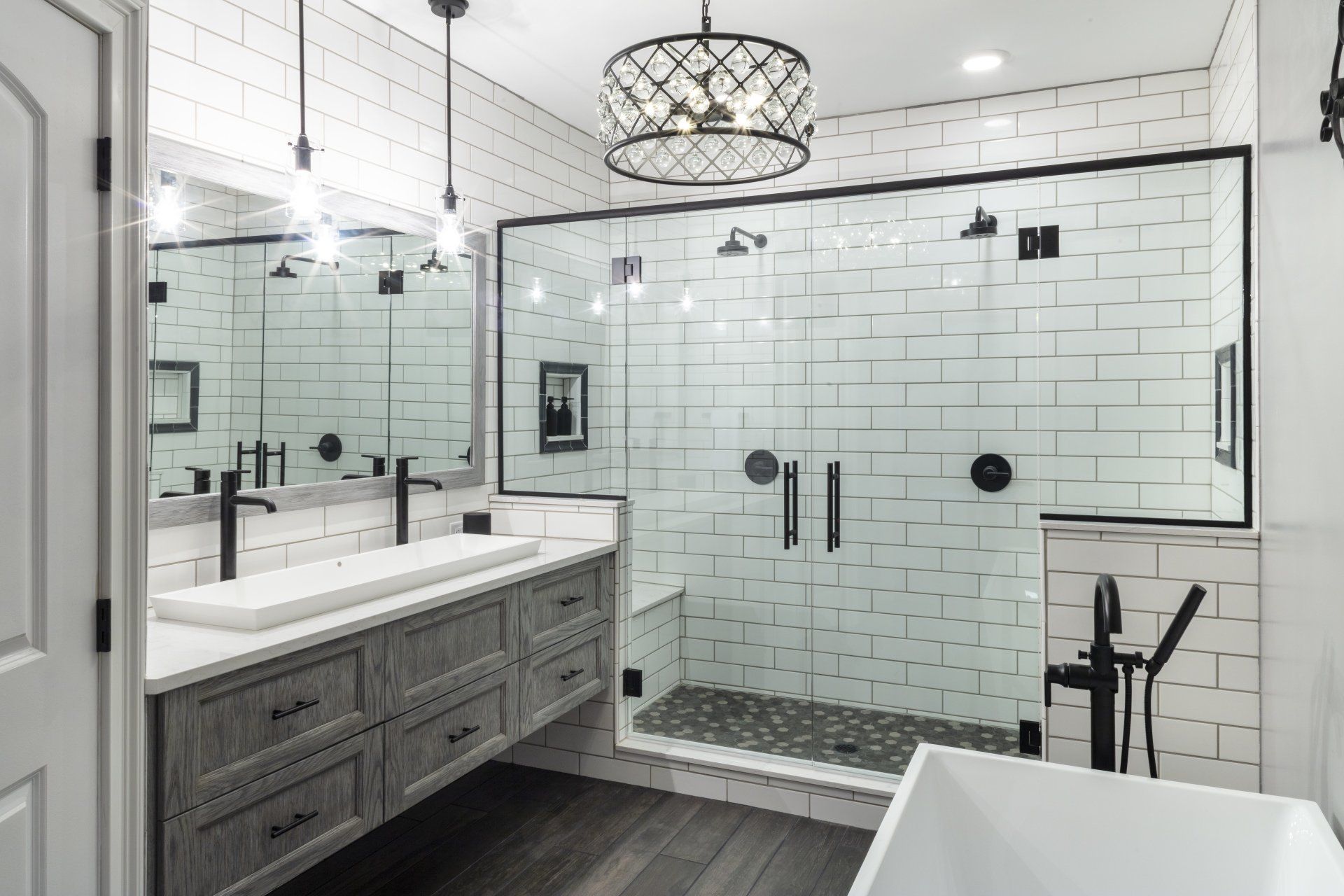 Modern bathroom with double vanity, glass shower, freestanding tub, and black-and-white tile accents