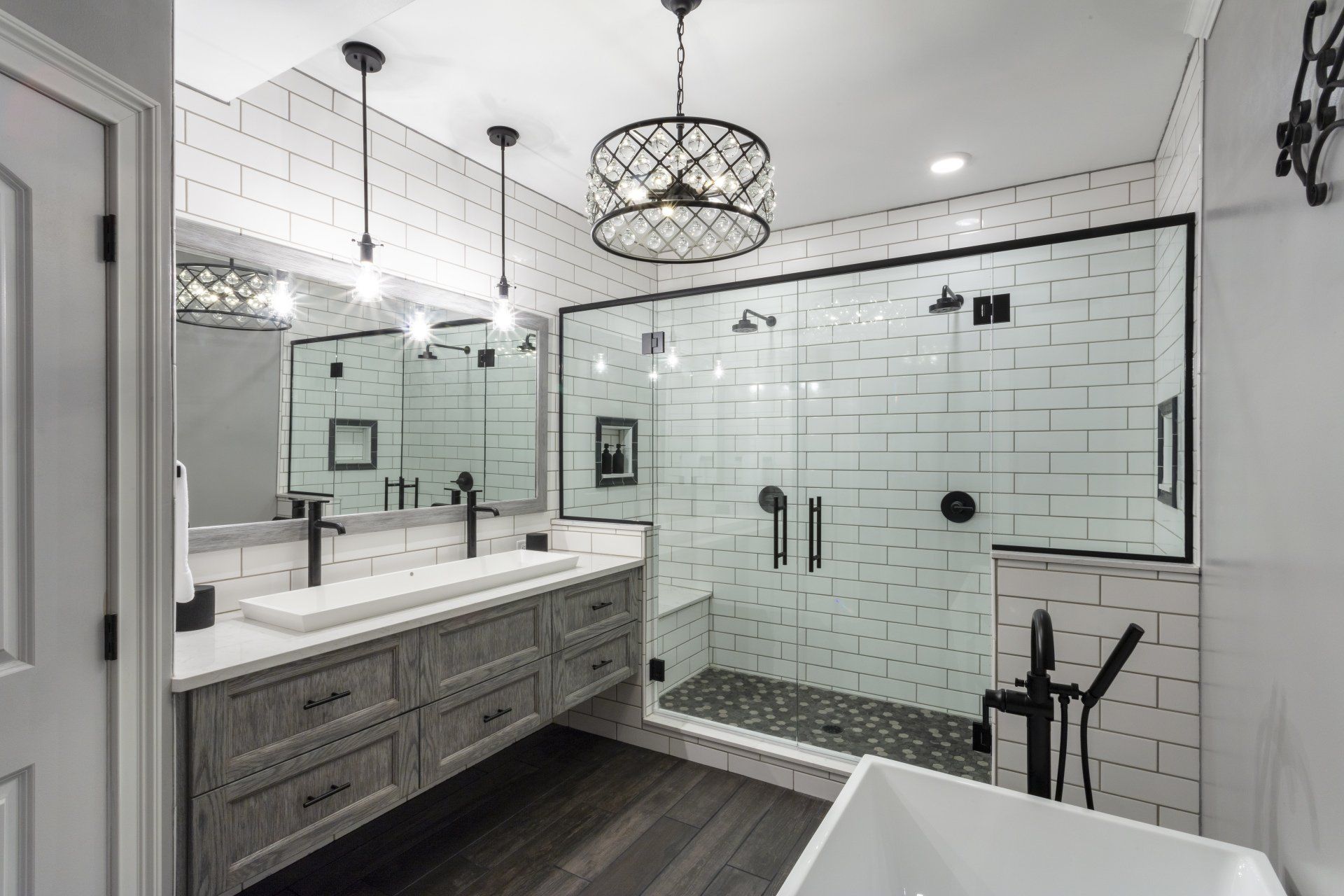 Modern bathroom with double vanity, glass shower, subway tile, and freestanding tub