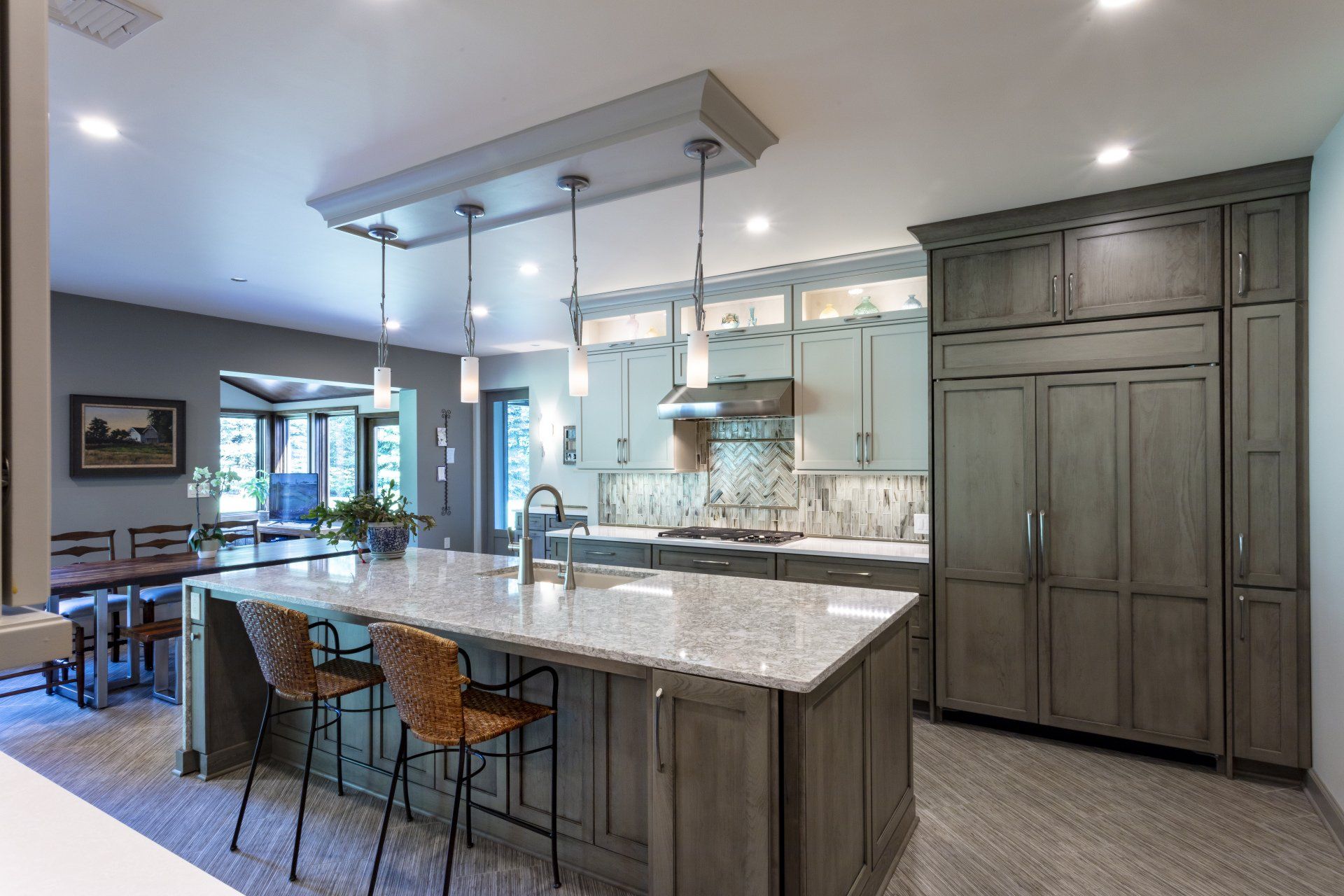 Modern kitchen with gray island, pendant lights, bar stools, and large pantry cabinets