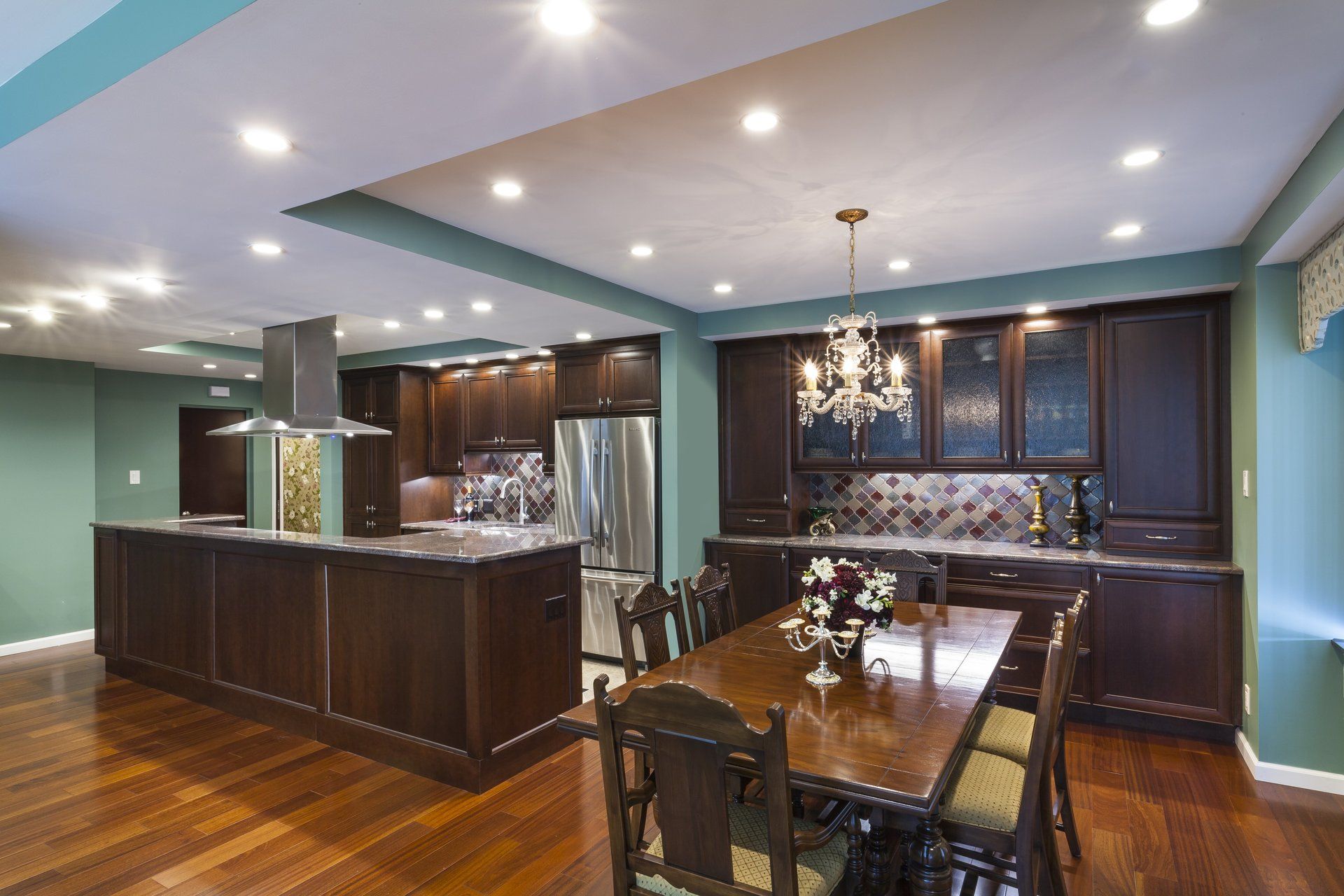 Modern kitchen and dining area with dark wood cabinets, recessed lighting, and a set dining table