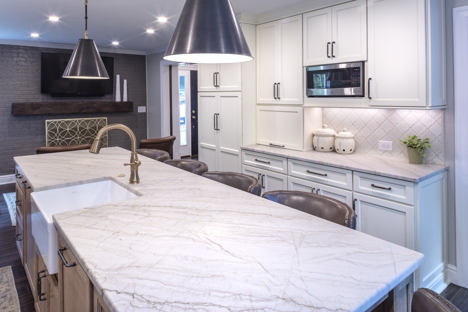 Modern kitchen with a large marble island, pendant lights, and white cabinetry
