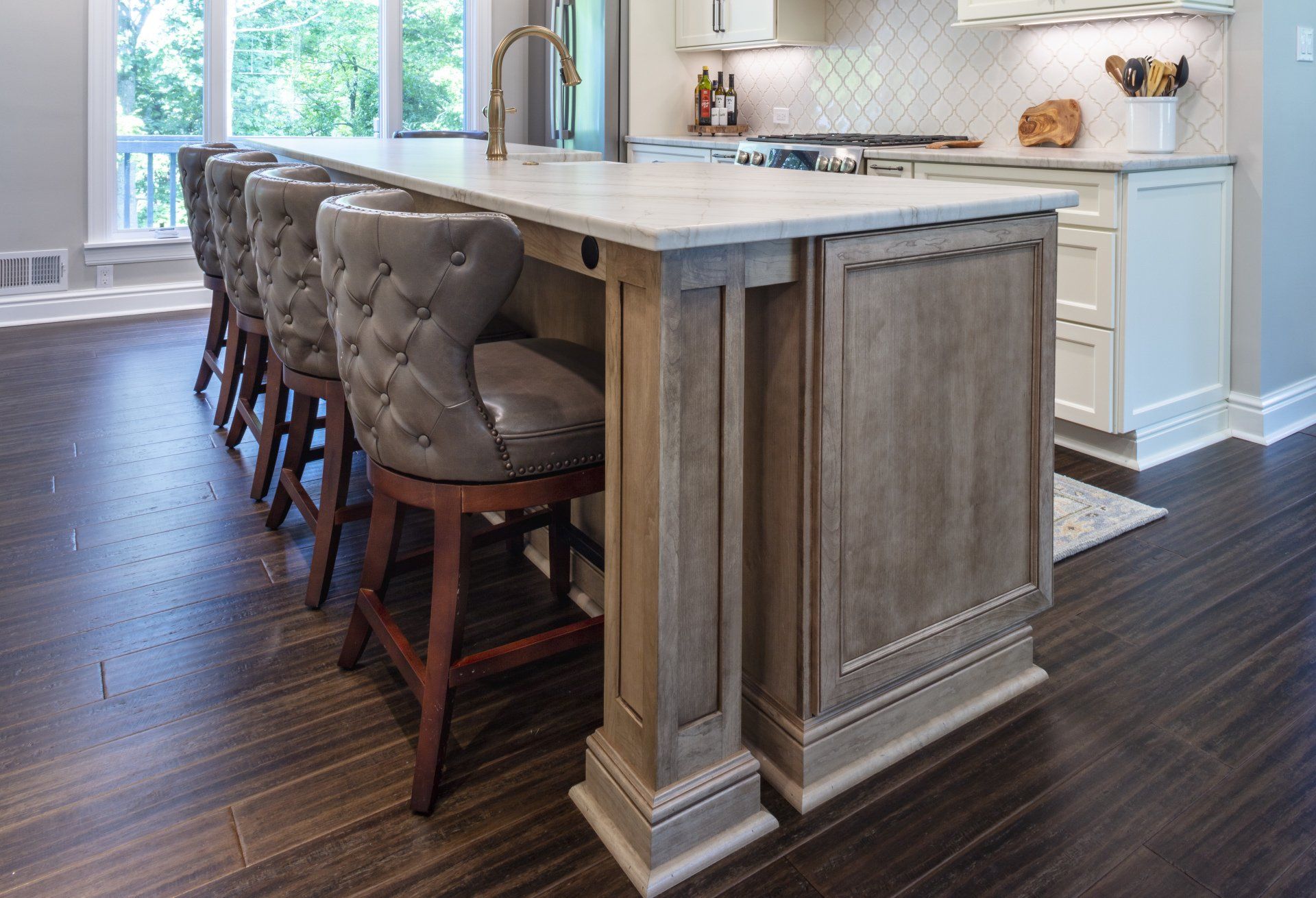 Modern kitchen with large island, tufted barstools, and dark wood floor