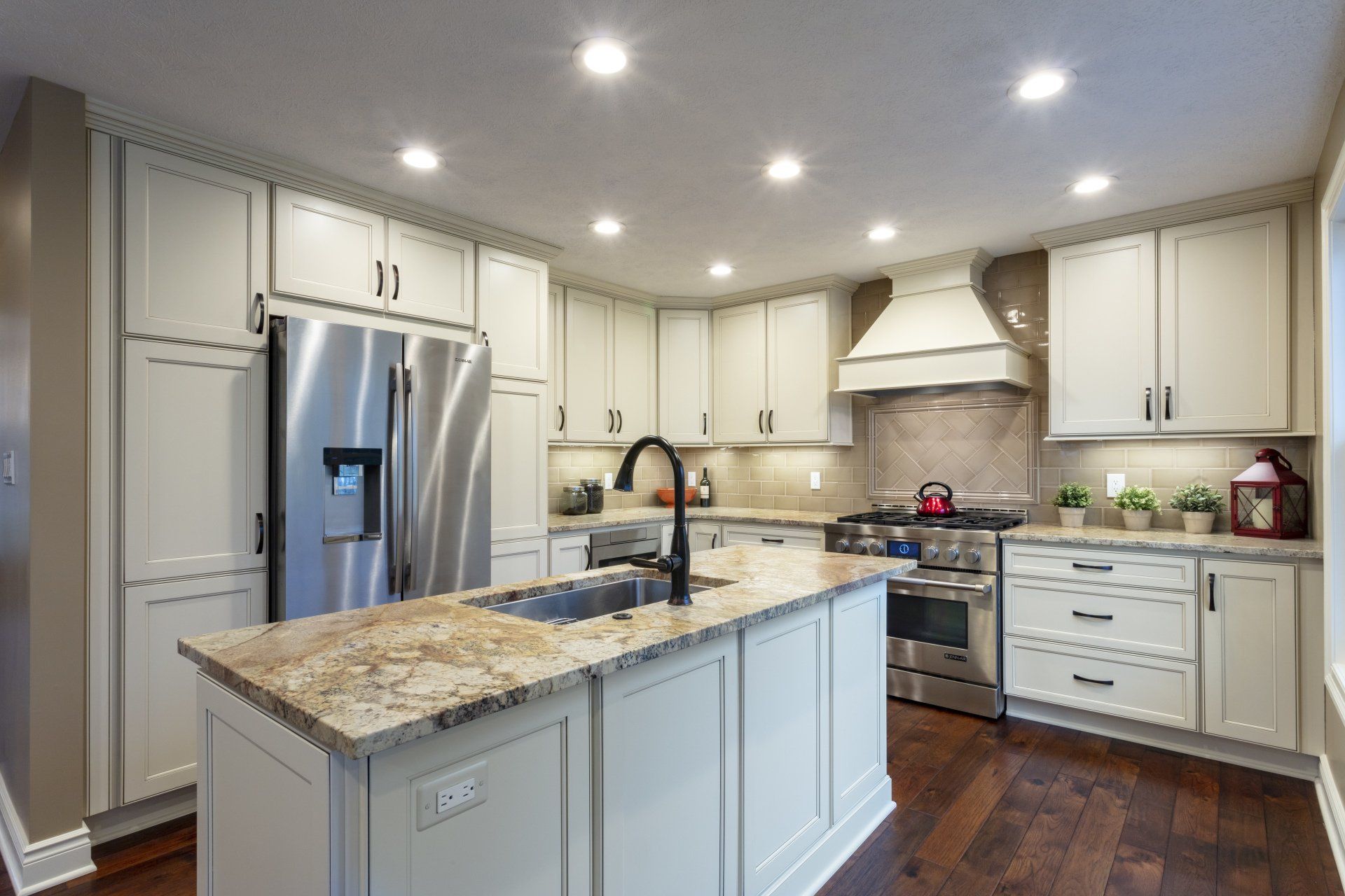 Modern kitchen with white cabinets, stainless steel appliances, granite island, and recessed lighting