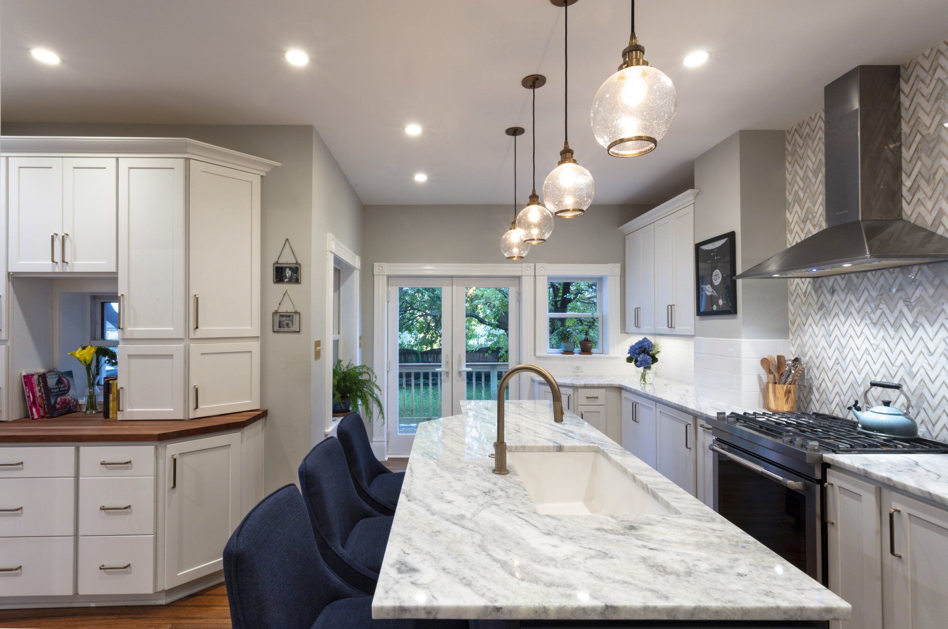 Modern kitchen with marble island, pendant lights, white cabinets, and stainless steel appliances
