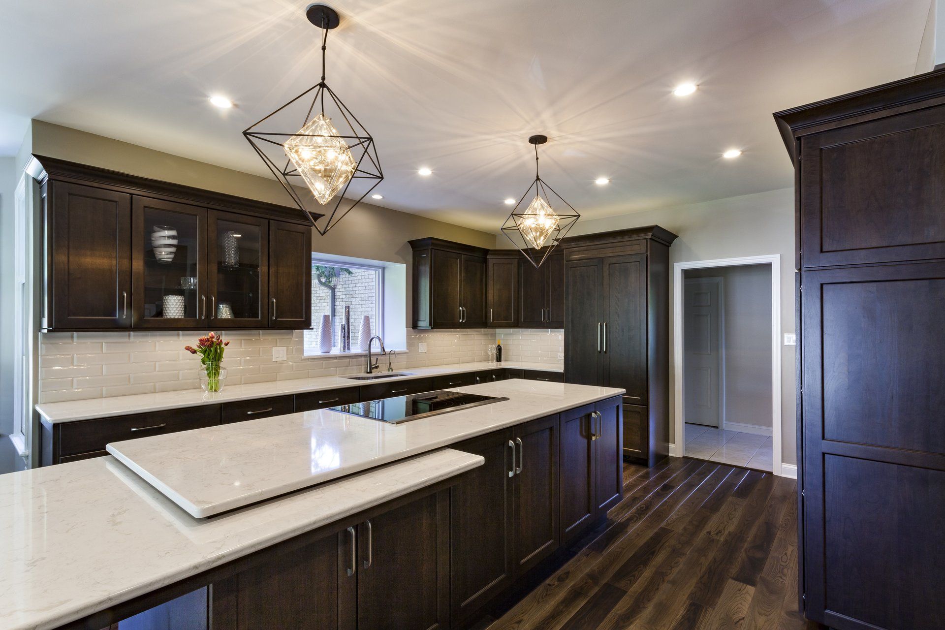A kitchen with dark wood cabinets and white counter tops.