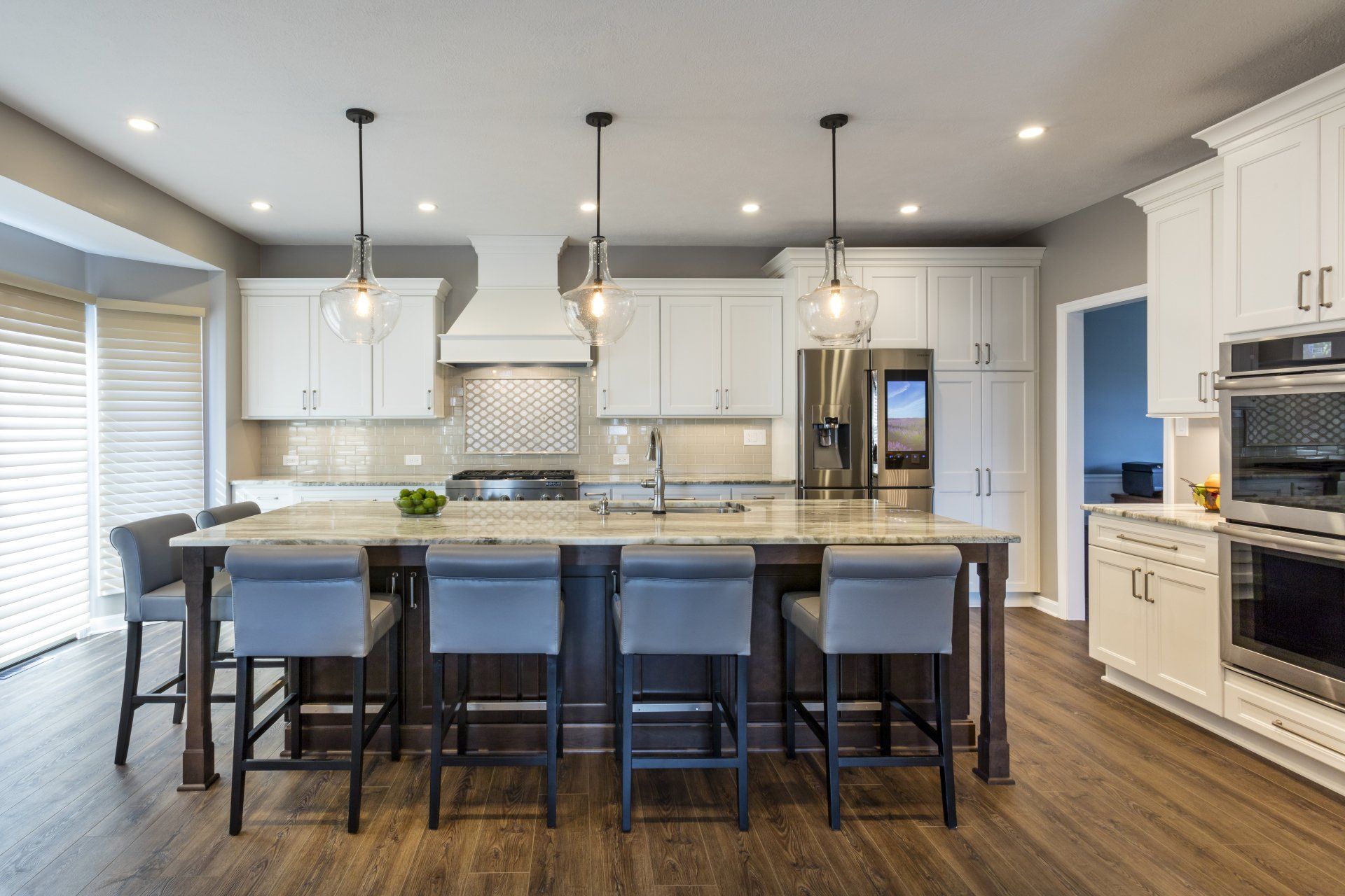 Modern kitchen with white cabinets, gray island, pendant lights, and dark wood flooring